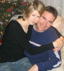 An ecstatic man smiles as his Canadian Christian fiancee sits on his lap at Christmas