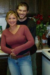 A man hugs a beautiful woman who smiles in the kitchen