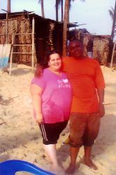 An interracial couple smile arm in arm on the beach