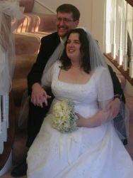 Nova Scotia Christian bride sits on the stairs with her new husband who holds her hand