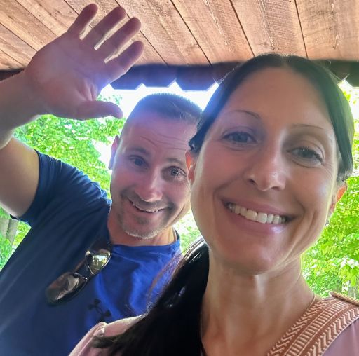 A man waves while photobombing a woman trying to take a selfie outdoors