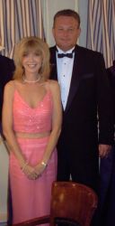 A woman in a beautiful pink wedding dress stands in front of a man in tuxedo