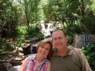 A Christian couple smile and cuddle together near a waterfall