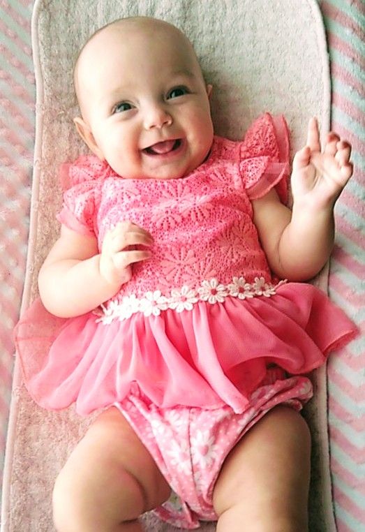 Laughing baby girl in pink lying down
