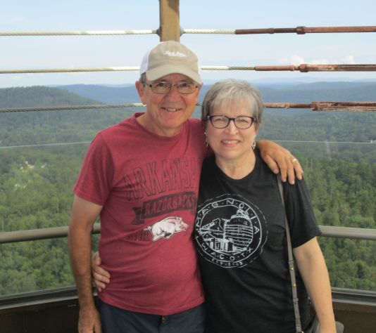15 years of marital bliss for smiling middle aged Christians who smile while posing over forest lookout