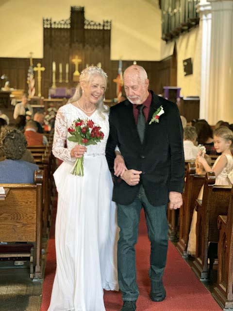 A mature Christian bride laughs as she walks arm in arm with her new husband