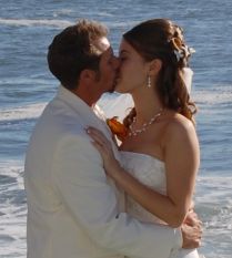 A couple kiss romantically by the ocean after marrying