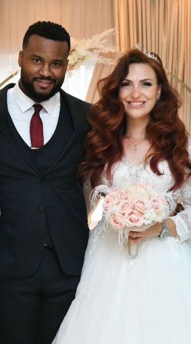 A very proud newly married man presents his new wife after marrying. The bride's long flowing curly ginger hair complements her beautiful rose bouquet