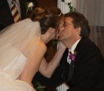 A new Christian bride holds her husband's face while kissing him tenderly