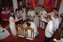 Couples pray together over a bride and groom who sit with bowed heads