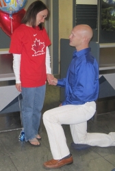 A man proposes on one knee to a woman wearing a Team Canada Jersey