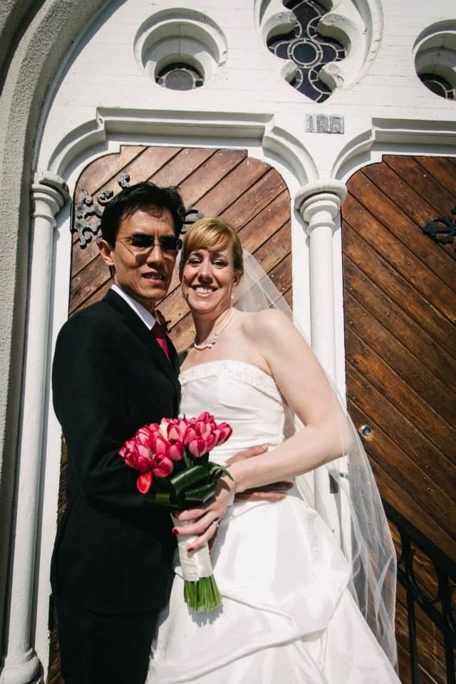 A happy Christian couple pose in front of an old church door on their wedding day