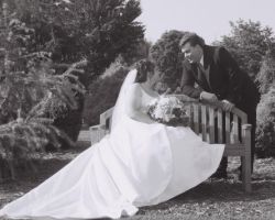 Christian man leans over a bench and talks to his pretty bride in a beautiful dress