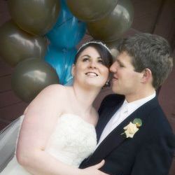 Groom whispers in his wife's ear as she smiles on their wedding day