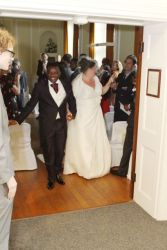 Wedding guests applaud a new bride and groom as they enter the reception hall