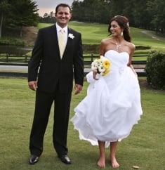 Barefoot bride stands on the grass and laughs next to her husband
