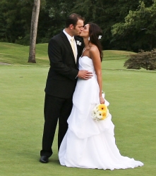 A new groom leans in and kisses his bride outdoors