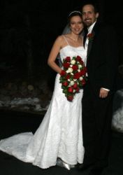 A super happy man smiles as her stands next to his beautiful bride, who holds her wedding bouquet