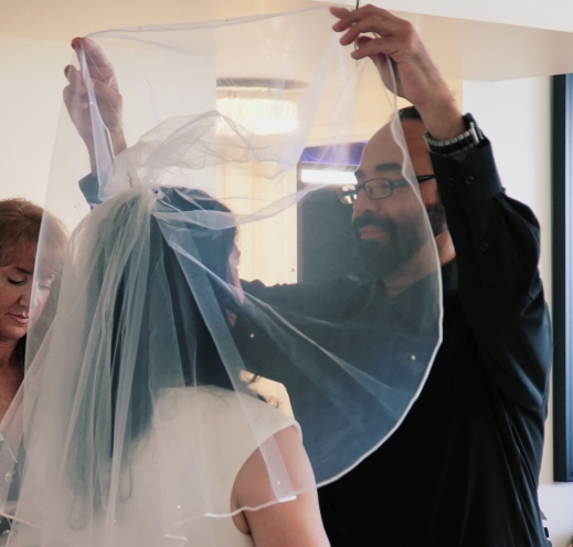 A groom lifts his wife's veil at their wedding ceremony