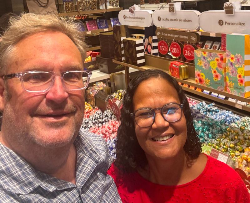 A newly engaged couple stand in front of a candy counter and smile
