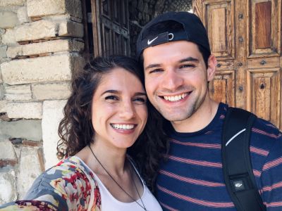 Beautiful Christian couple taking selfie on vacation in front of old wooden door while smiling