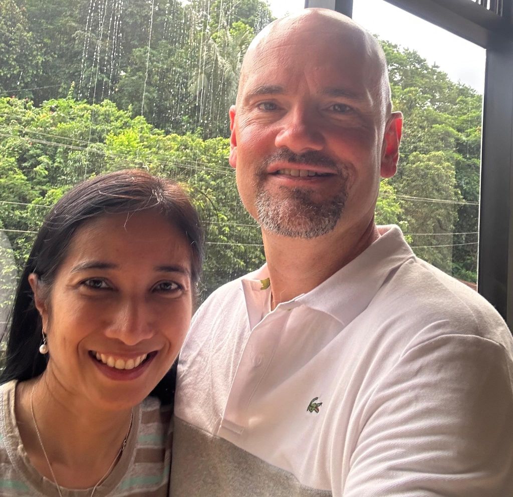 A handsome Christian man takes a selfie indoors with a pretty woman, with a forest in the background