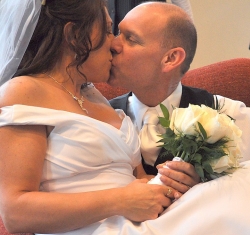 A bride overcome with joy leaps into her husband's arms and kisses him while still holding her bouquet