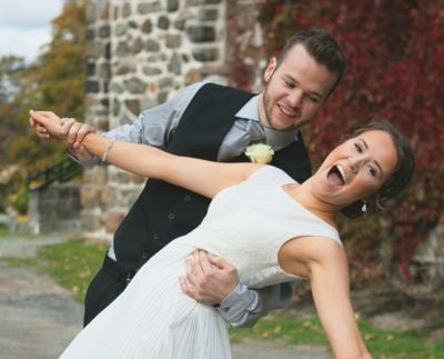 A groom dips his bride who giggles uncontrollably