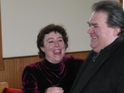 A man giggles while his wife looks at him and laughs