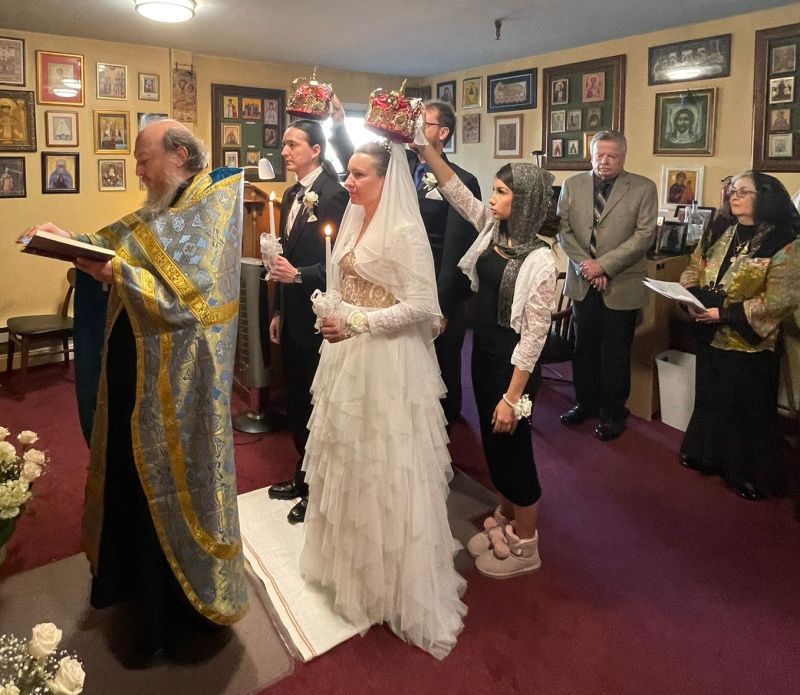 A Christian Orthodox couple are crowned while the wedding priest reads while facing away
