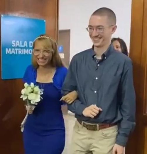 A newly engaged Christian couple beam with joy as they enter a room arm in arm