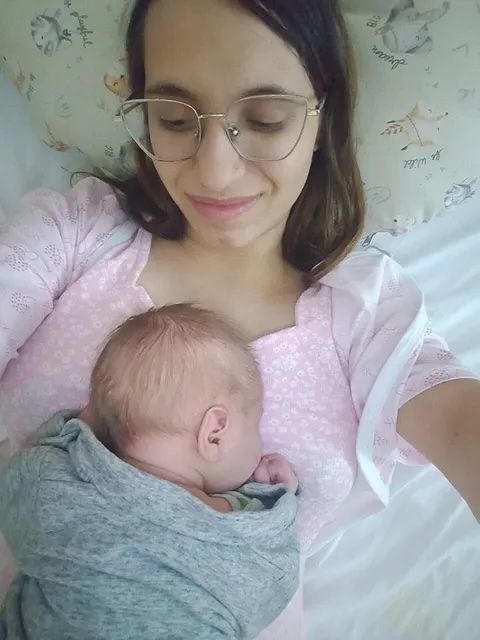 A tired but healthy mother holds her newborn in bed