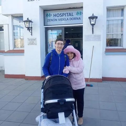 A young married couple huddle for warmth outside the hospital with their baby in a stroller