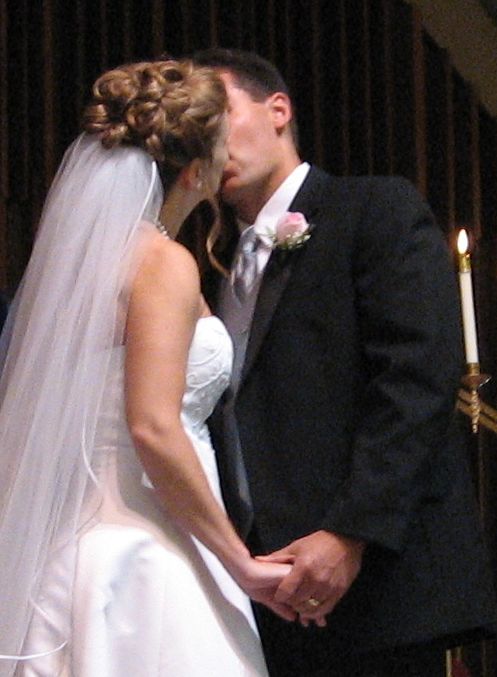 A bride in a strapless wedding dress kisses her new husband just after marrying
