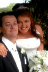 An excited Australian Christian bride smiles broadly with her arm around her new husband