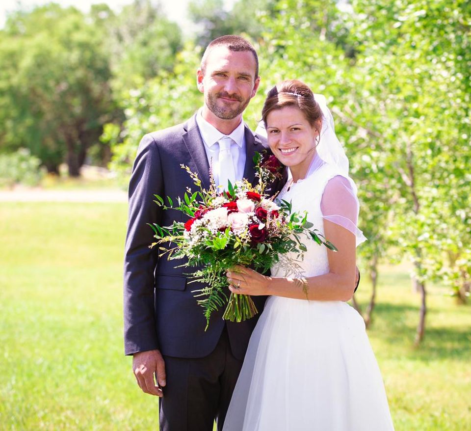 Young Manitoba Christian singles just married, holding bouquet while posing outdoors