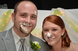 A young Christian couple laugh with wedding cake all over their faces
