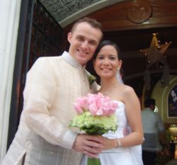 Interracial Christian couple smile and hold bride's wedding bouquet