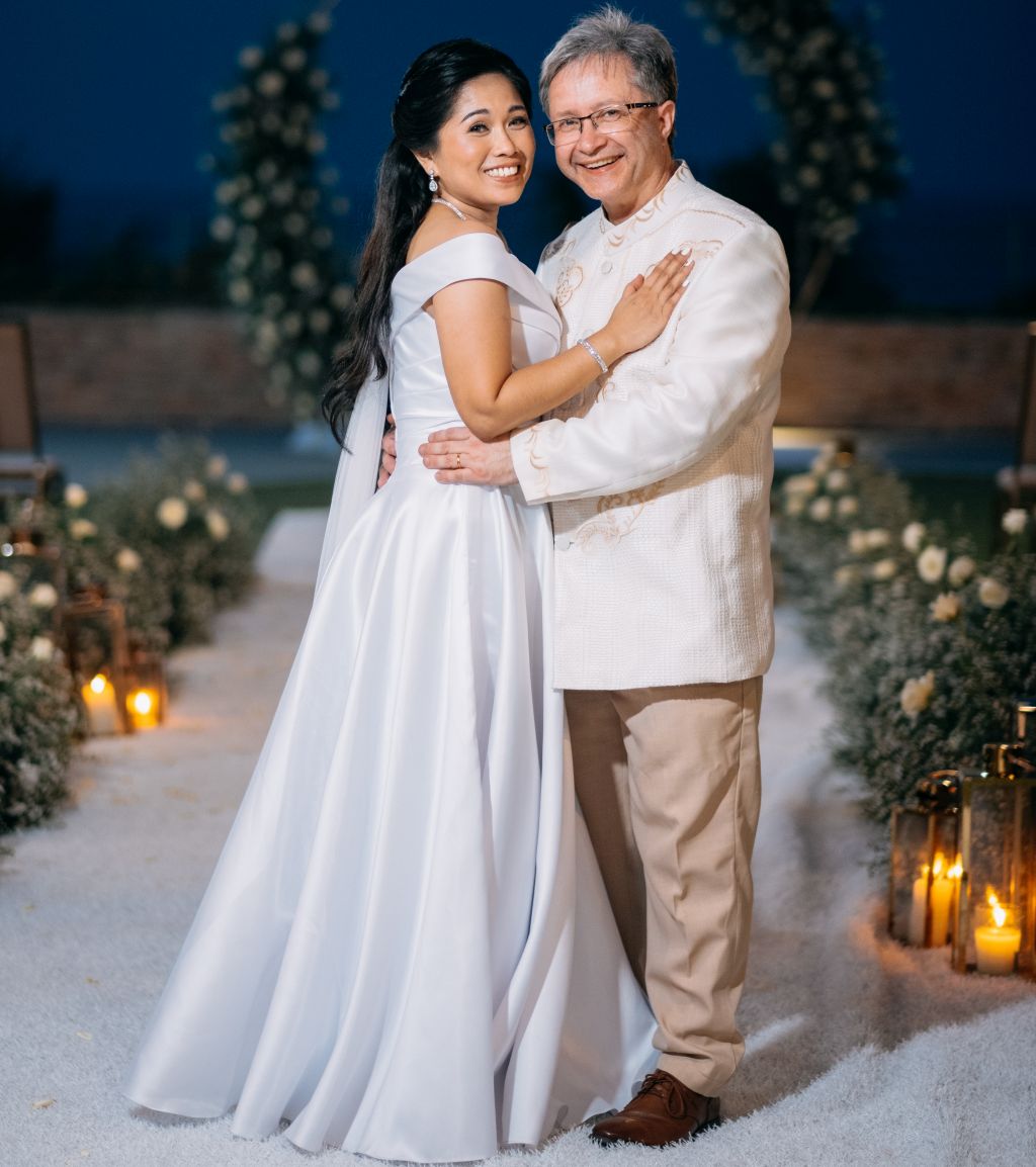 A groom in a white shirt beams as he holds his beautiful bride after marrying