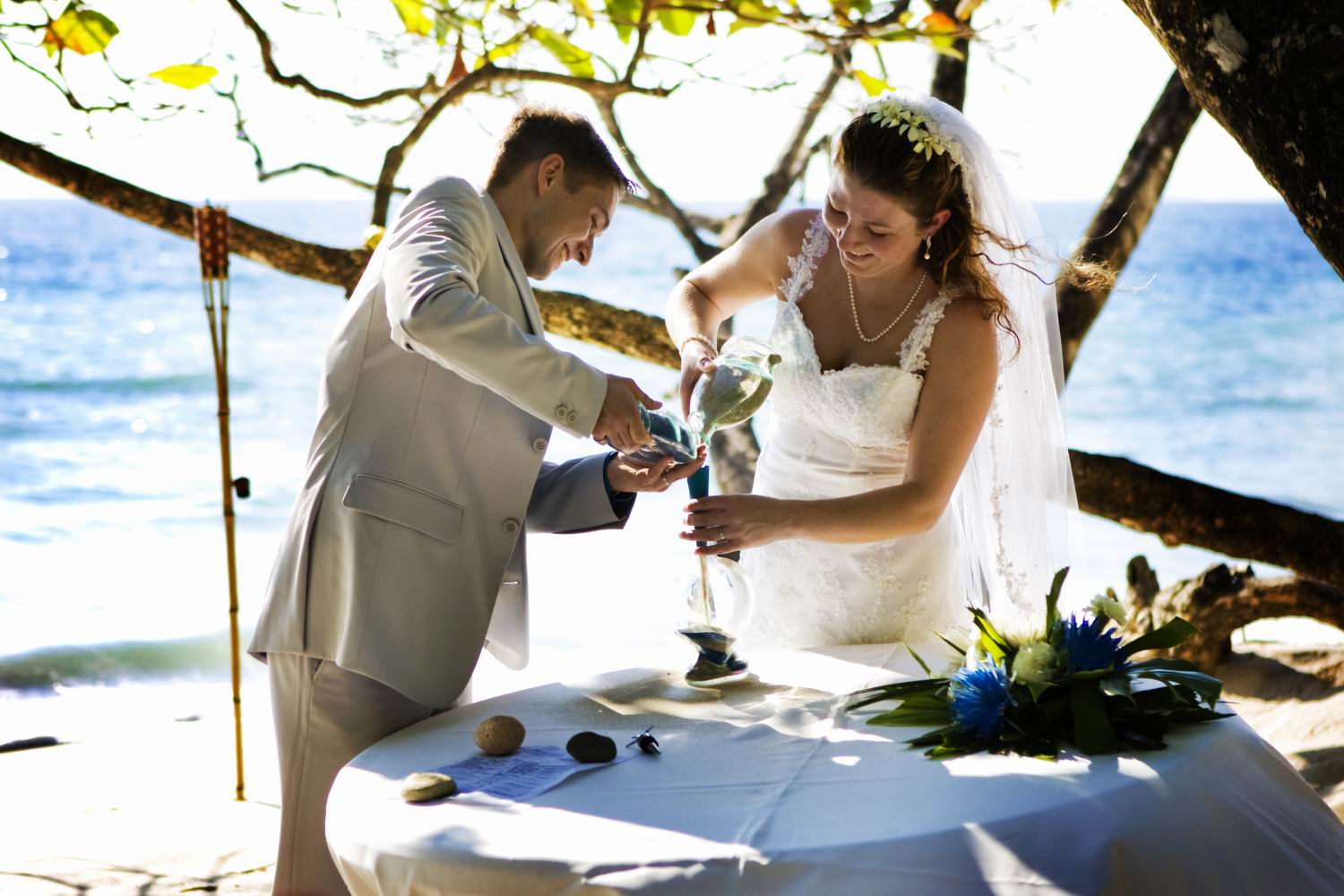 Bride and groom pour sand into marriage bottle at beach wedding