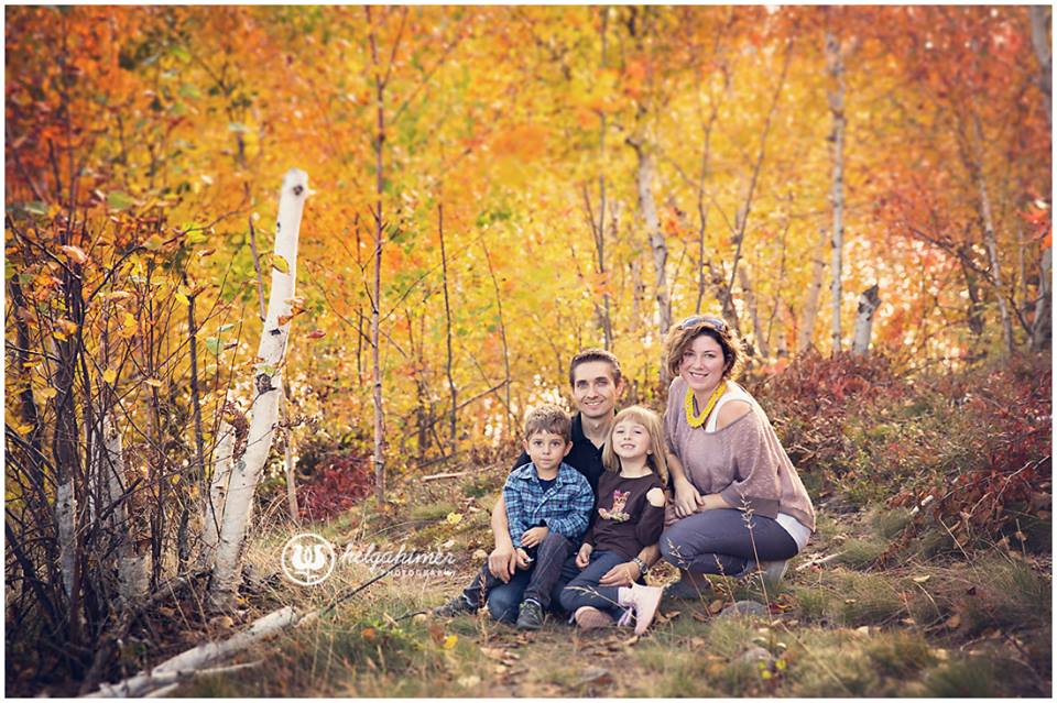 A beautiful Christian family sit and hug in an Autumn forest