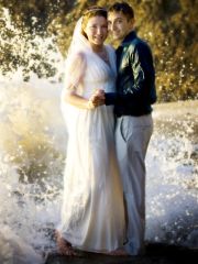 Great shot of newly married couple posing with waves crashing behind them