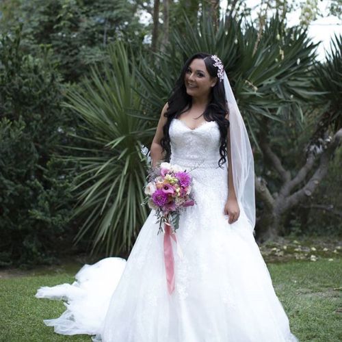 Beautiful Christian bride poses in dress holding bouquet in tropical setting