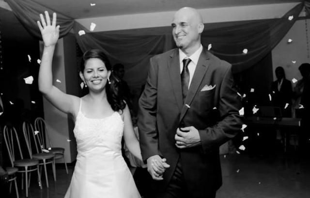 A Brazilian Christian woman holds her hand up in victory while the other holds her new husband, who laughs and walks proudly