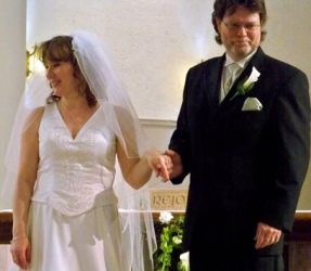 A very proud man holds his wife's hand on their wedding day