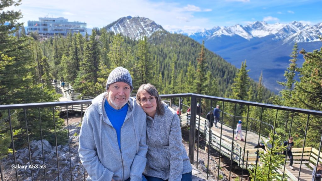 A couple poses in sweaters at a lookout in Banff National Park