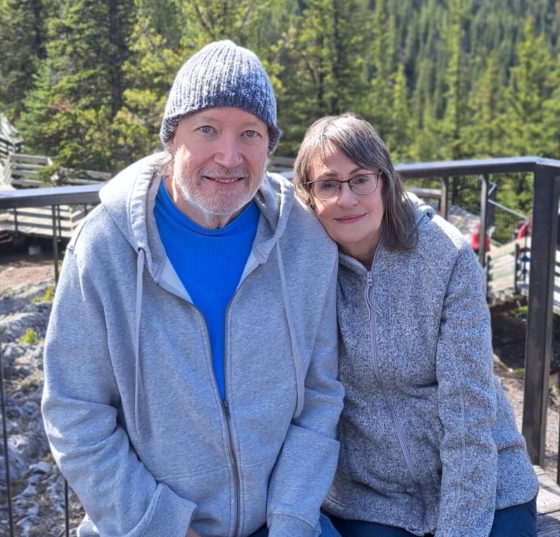 A woman leans her head against a man wearing a toque while they're in Banff