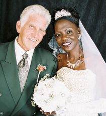 A very happy man leans next to a beautiful Christian woman in bridal dress and veil