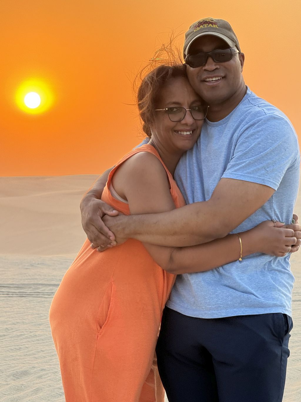 A beautiful Black Christian couple hug under a gorgeous sunset in Qatar