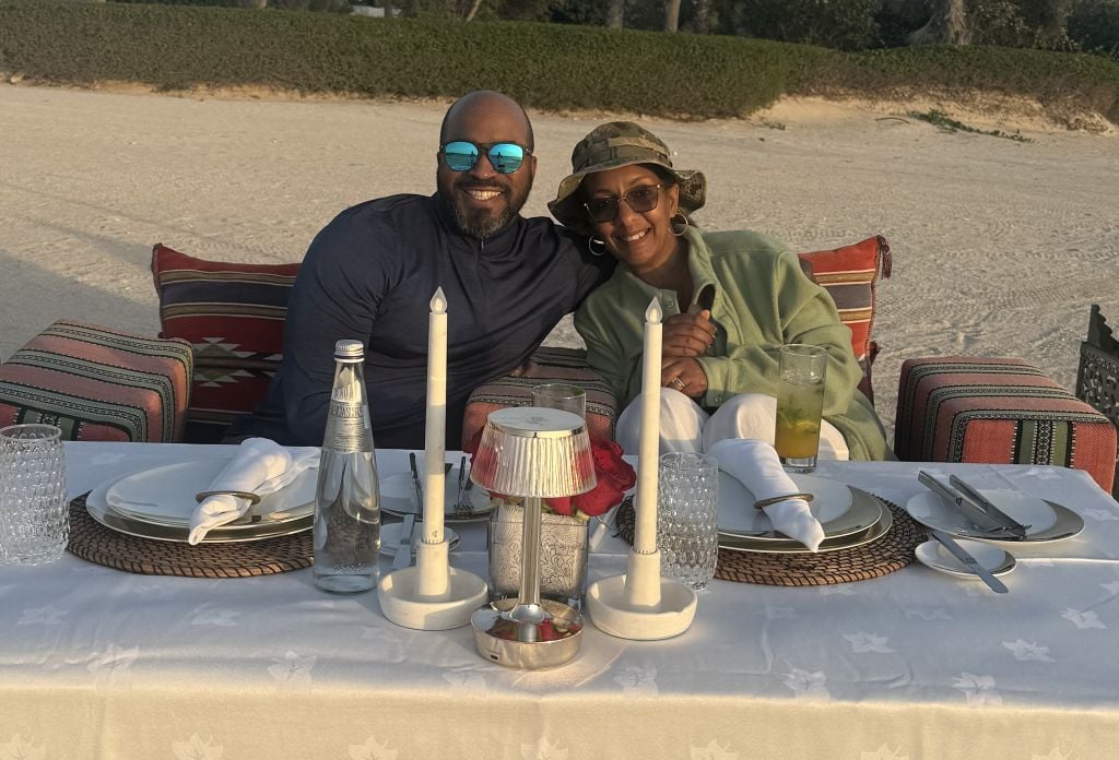 An American Christian man enjoys a romantic candlelit anniversary dinner on the beach with his African wife